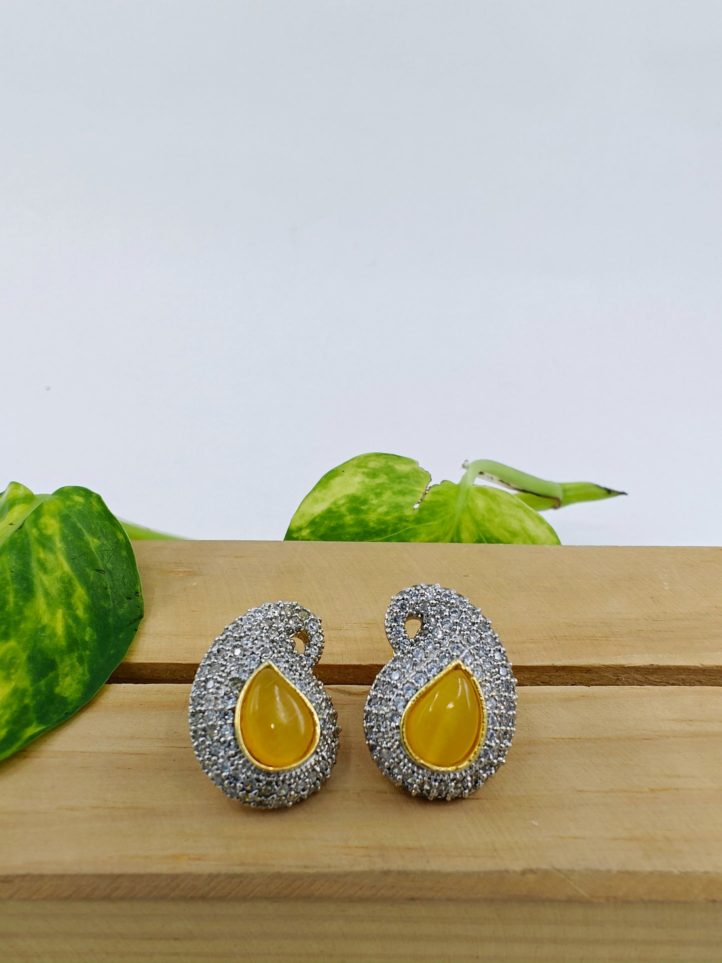 Earrings in golden finish with piasley design,coloured stone in centre surrounded by CZ