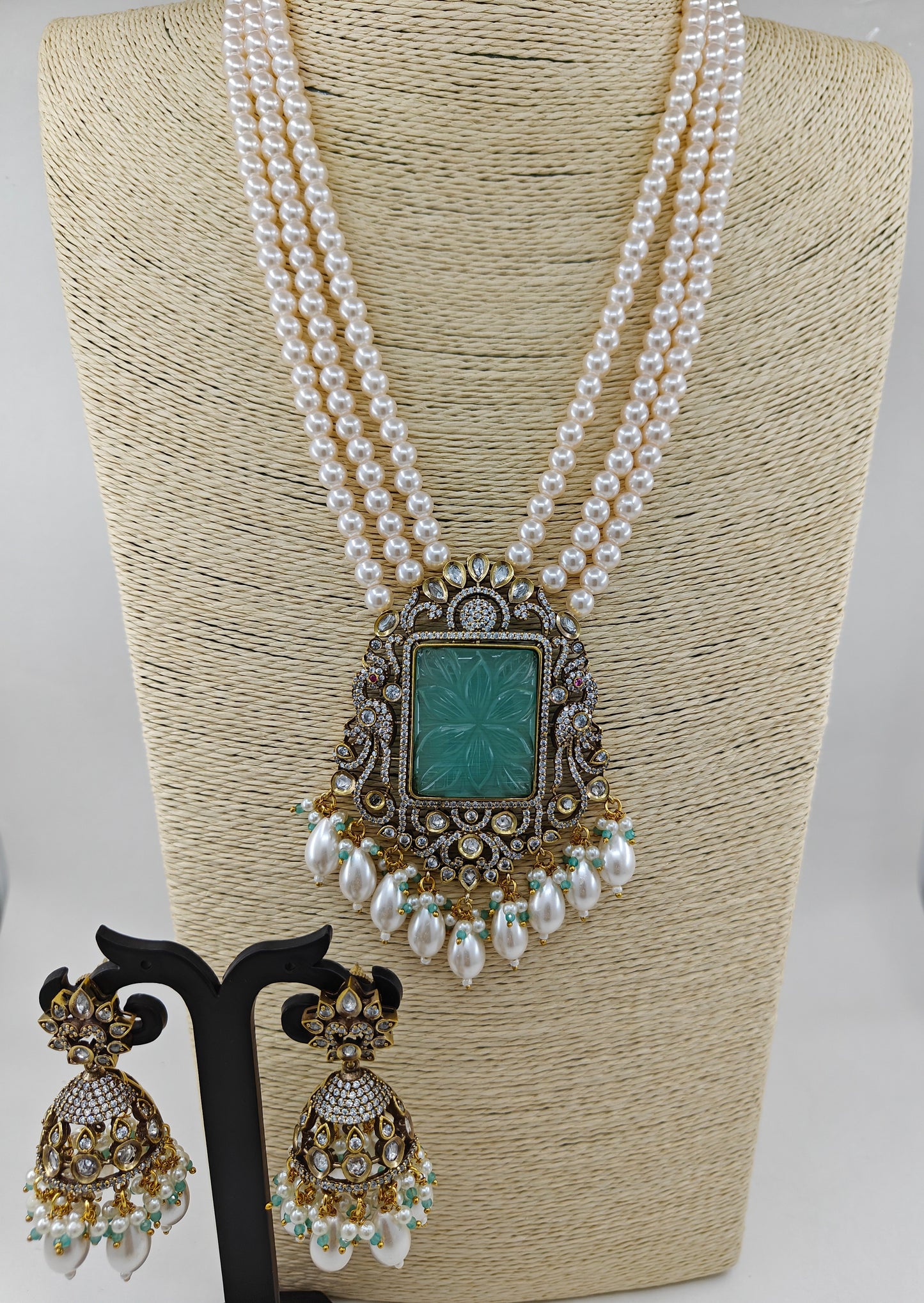 Set in antique finish with a mint stone pendant with kundan and CZ on pearl strands, matching jhumkas(earrings)