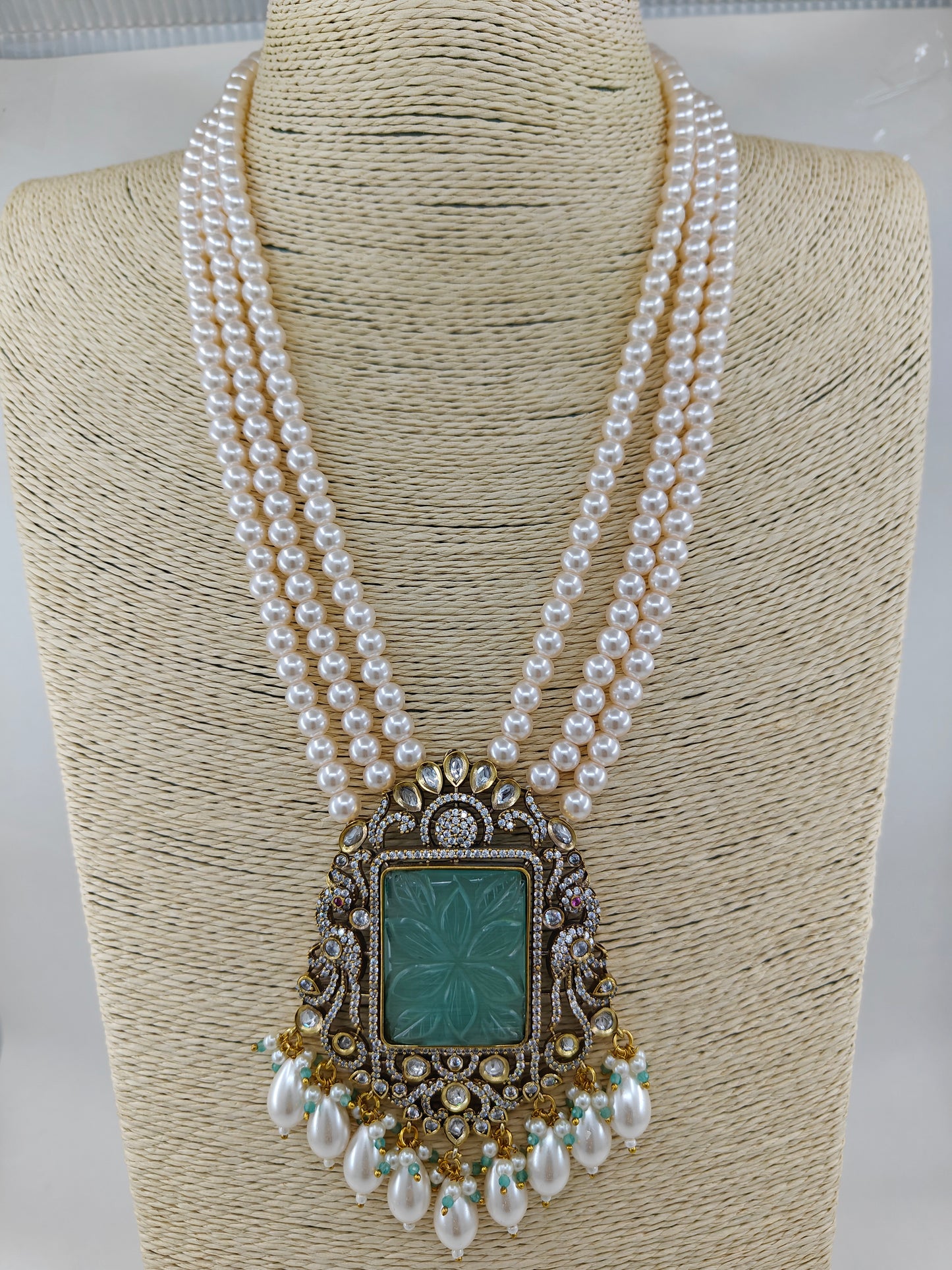 Set in antique finish with a mint stone pendant with kundan and CZ on pearl strands, matching jhumkas(earrings)