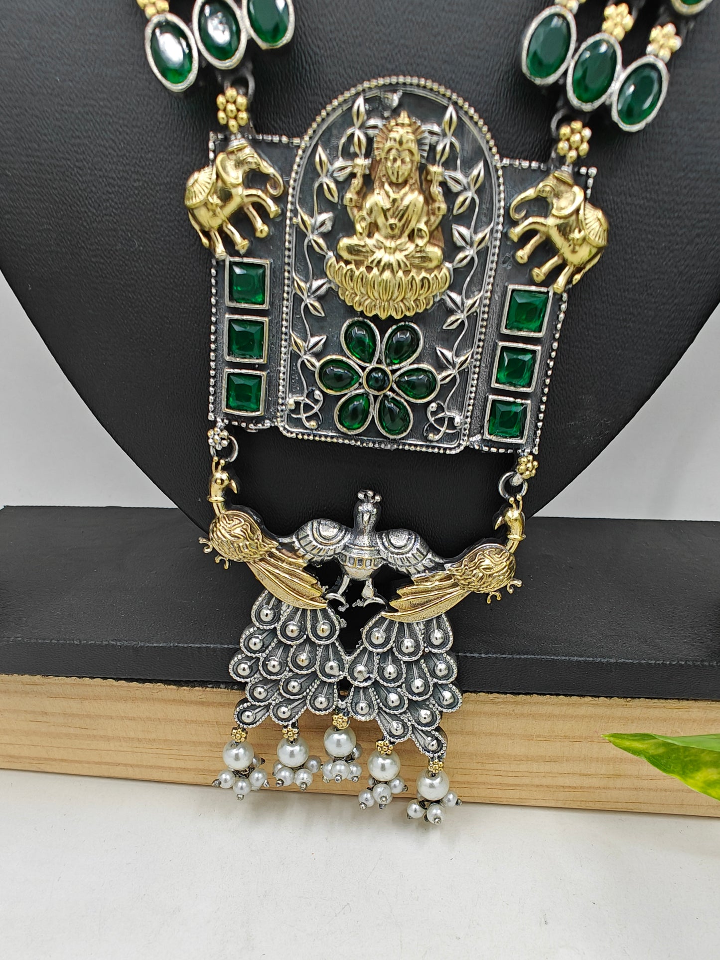 Dual tone chunky long necklace with emerald green stone inlay.The pendant depicts garud and has laksmi on it