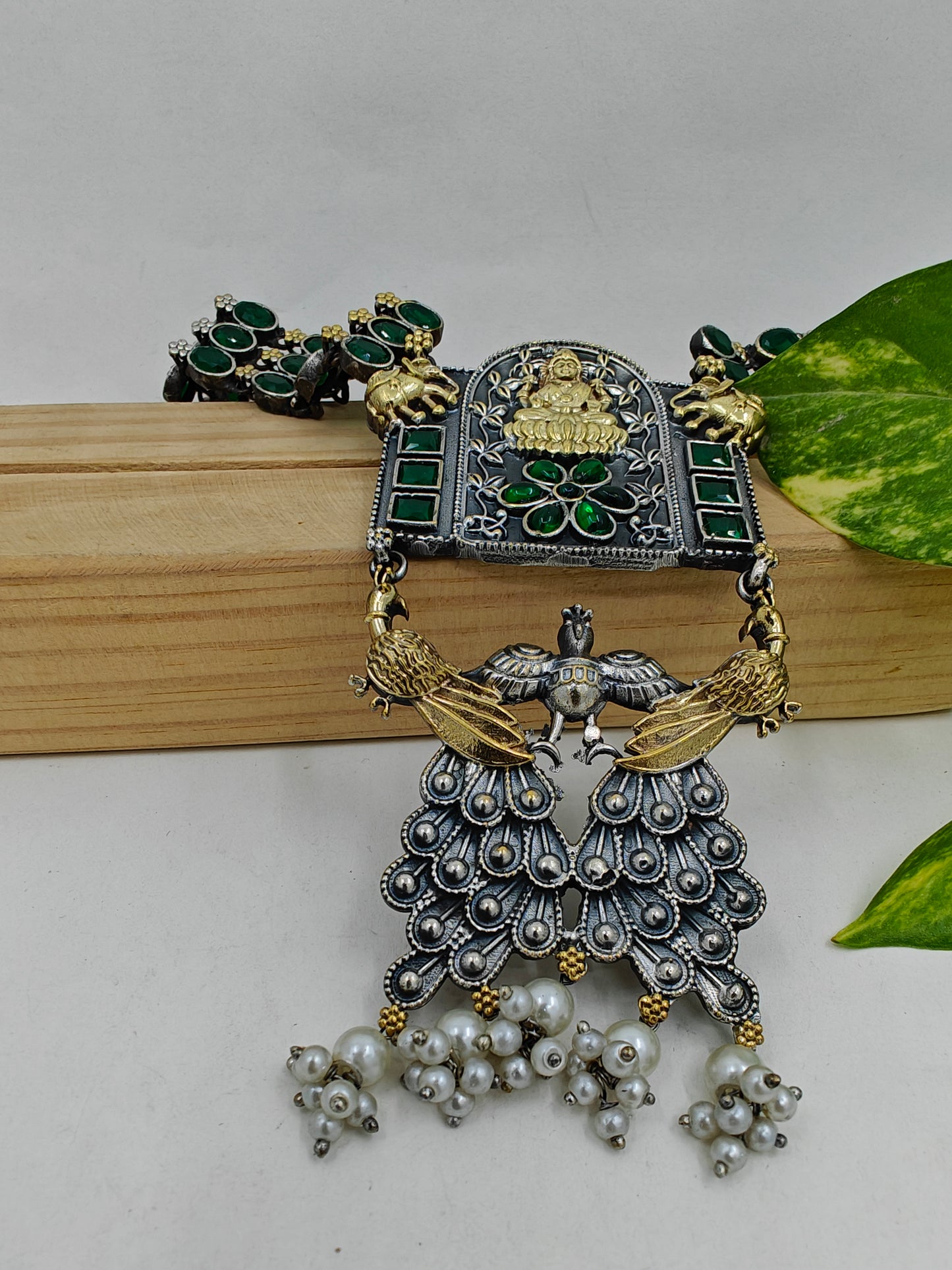 Dual tone chunky long necklace with emerald green stone inlay.The pendant depicts garud and has laksmi on it