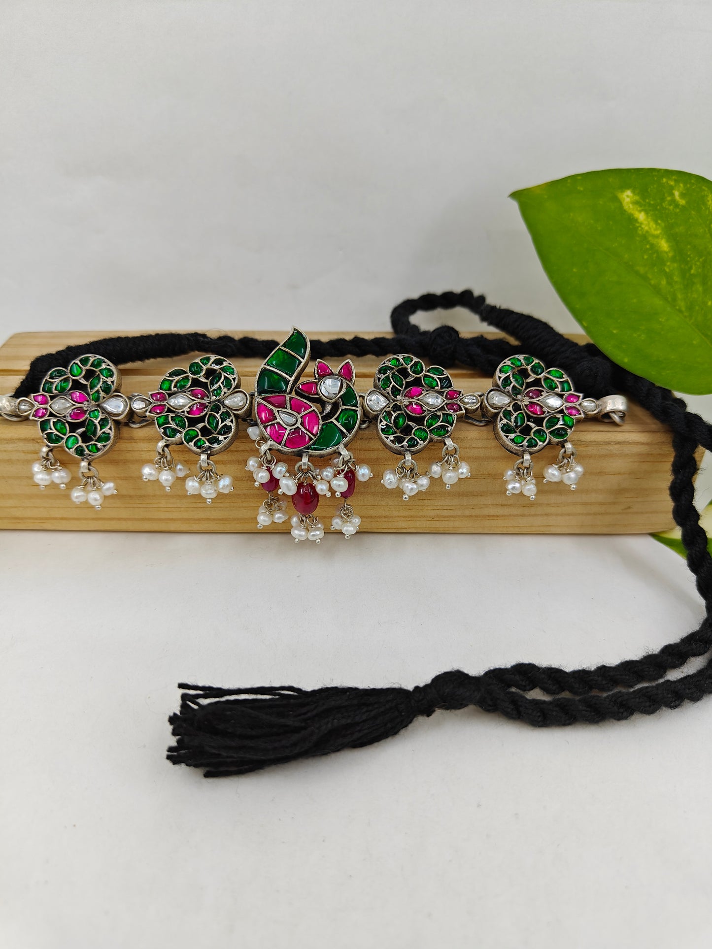 Silver choker necklace with a peacock centerpiece studded with ruby pink and emerald green stones