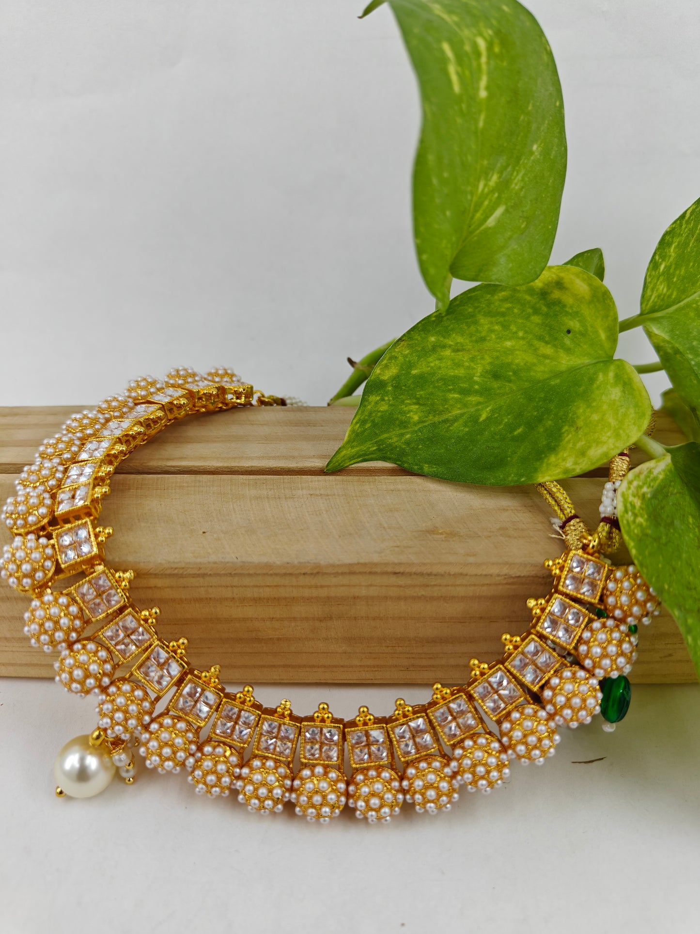 Gold finish set with red/ clear stones set in square design,embedded pearl balls at the bottom complete the set.