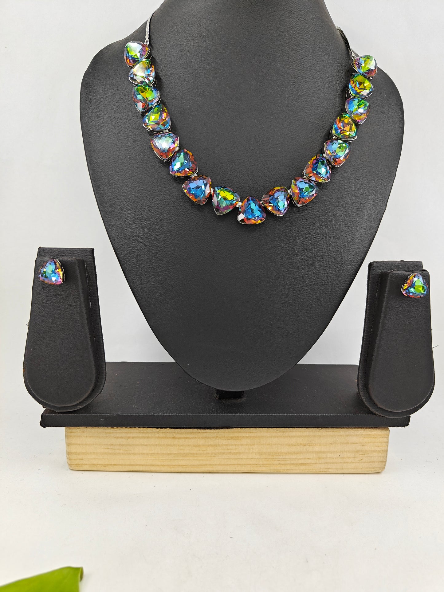 Set with triangular crystal in greenish white hue/green orange hue , matching studs