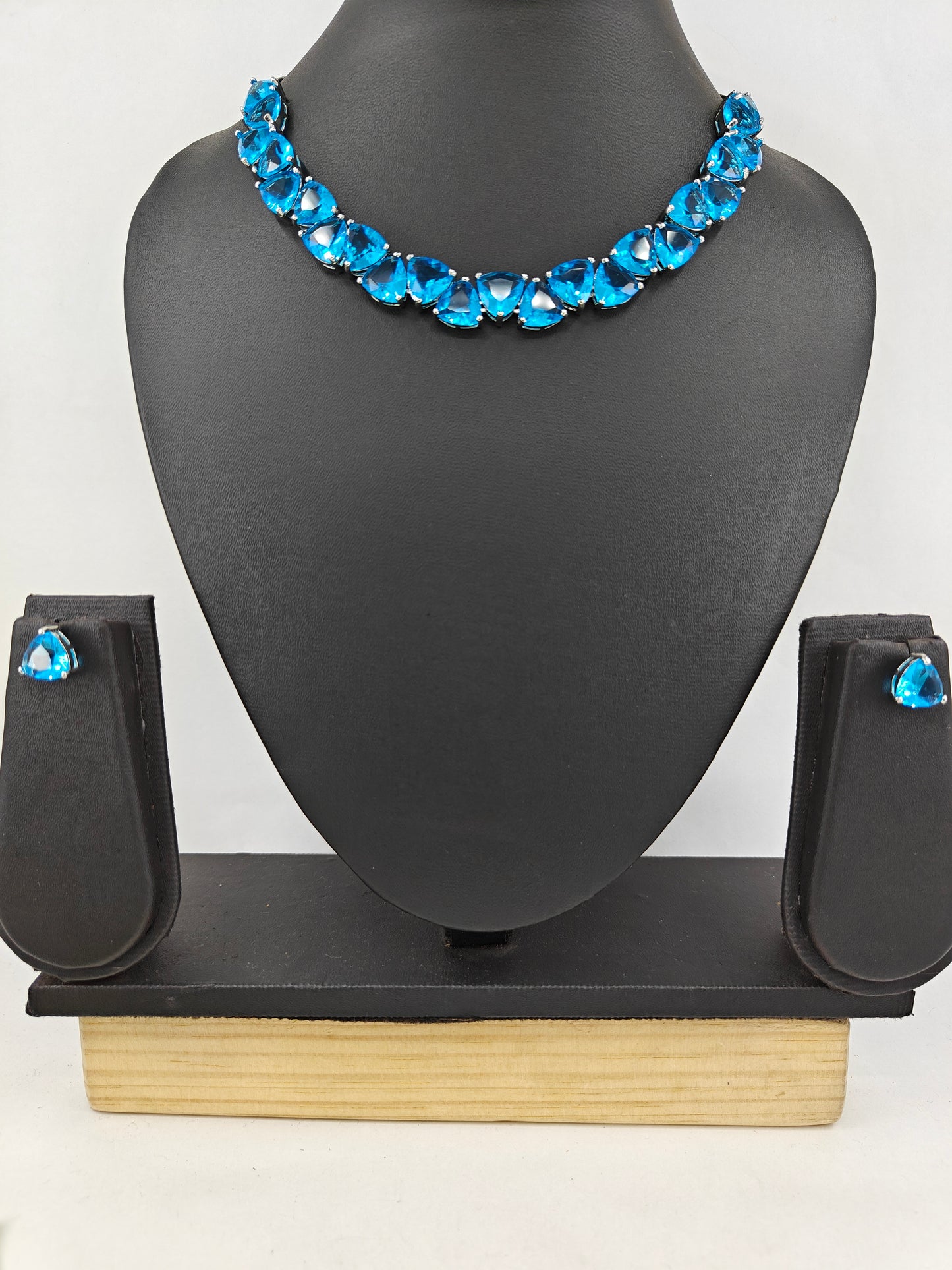 Set in platinum finish with triangular emerald green/ aqua blue stones matching studs