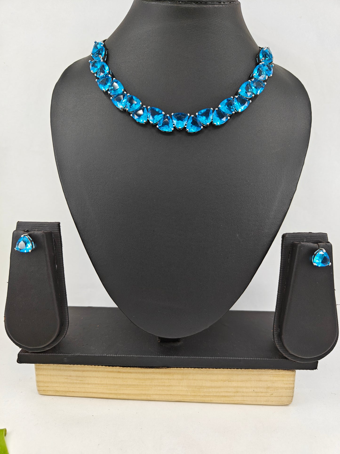 Set in platinum finish with triangular emerald green/ aqua blue stones matching studs