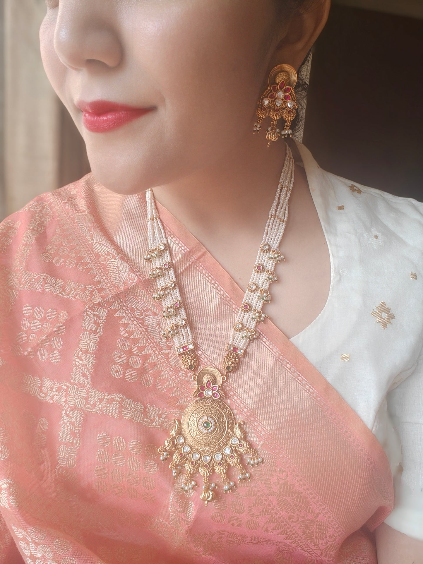 A kundan and pearl work set with a gold finish pendant on poth pearl strings with pachi kundan work