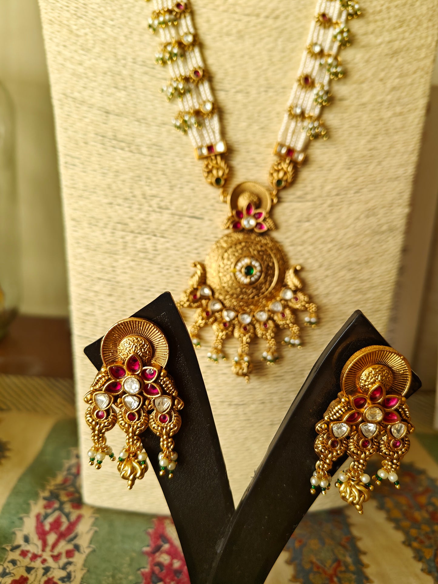A kundan and pearl work set with a gold finish pendant on poth pearl strings with pachi kundan work