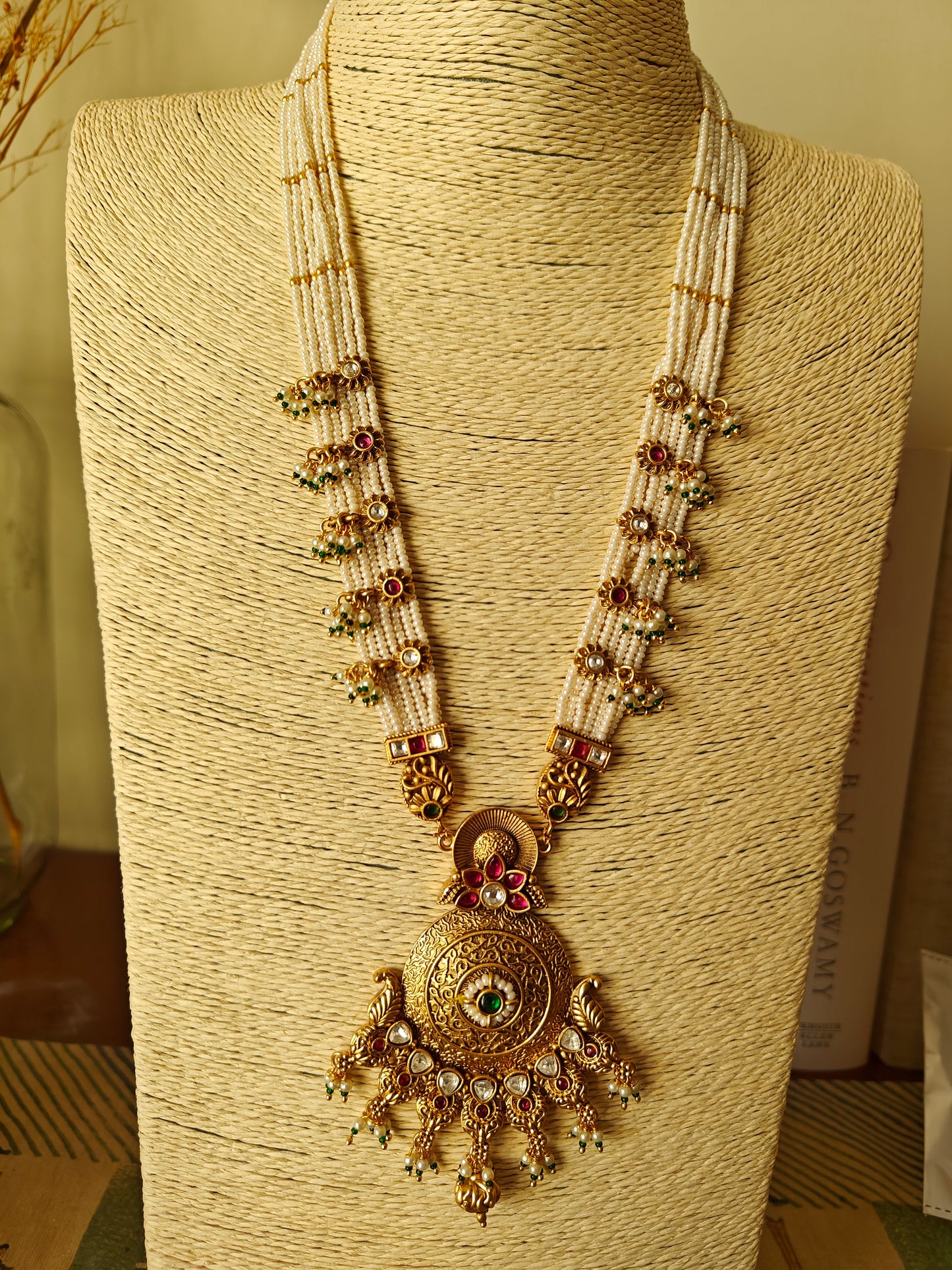 A kundan and pearl work set with a gold finish pendant on poth pearl strings with pachi kundan work