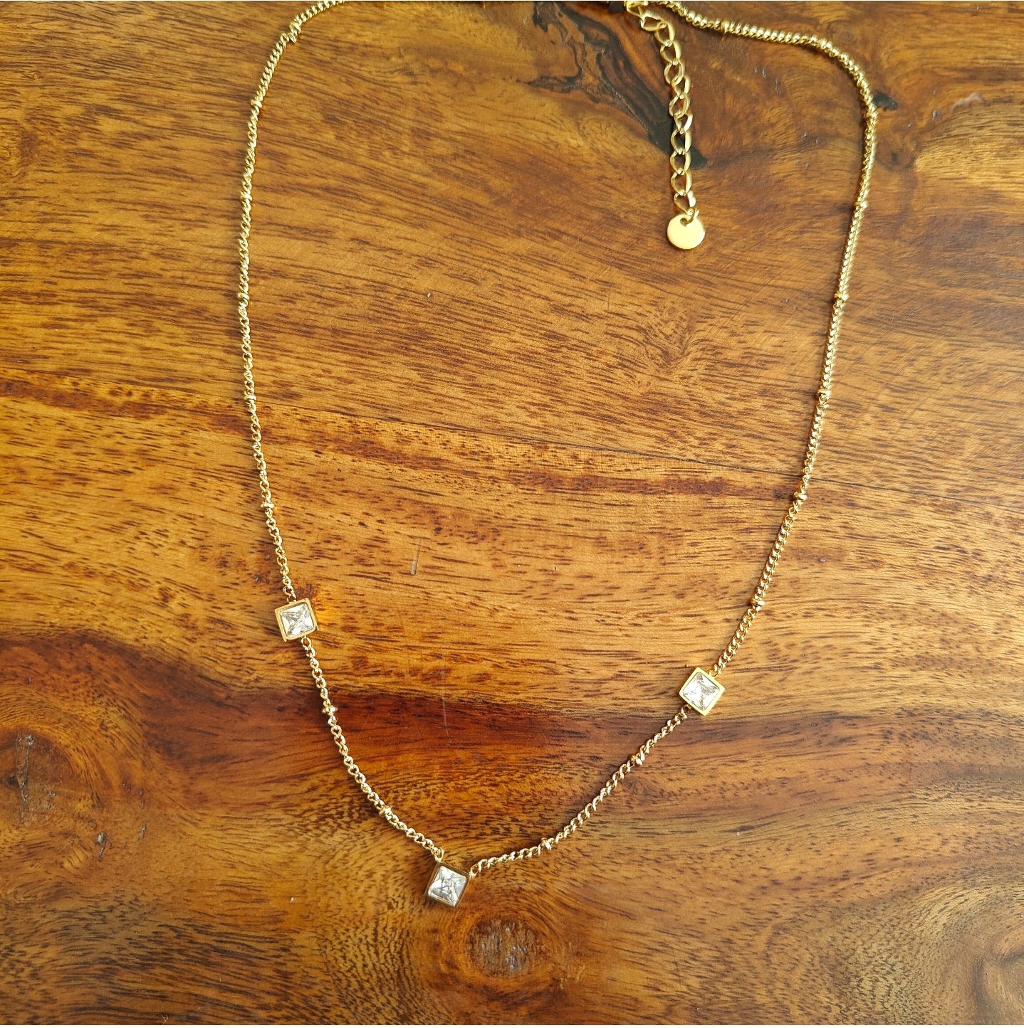 Gold chain with suspended square pieces with stones
