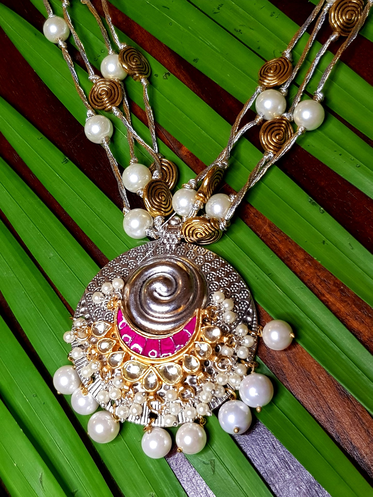 A funky set in silver finish with pearls and golden coils on multiple strings ,a pendant with red/green stone,kundan and pearls,Big earring/jhumkis