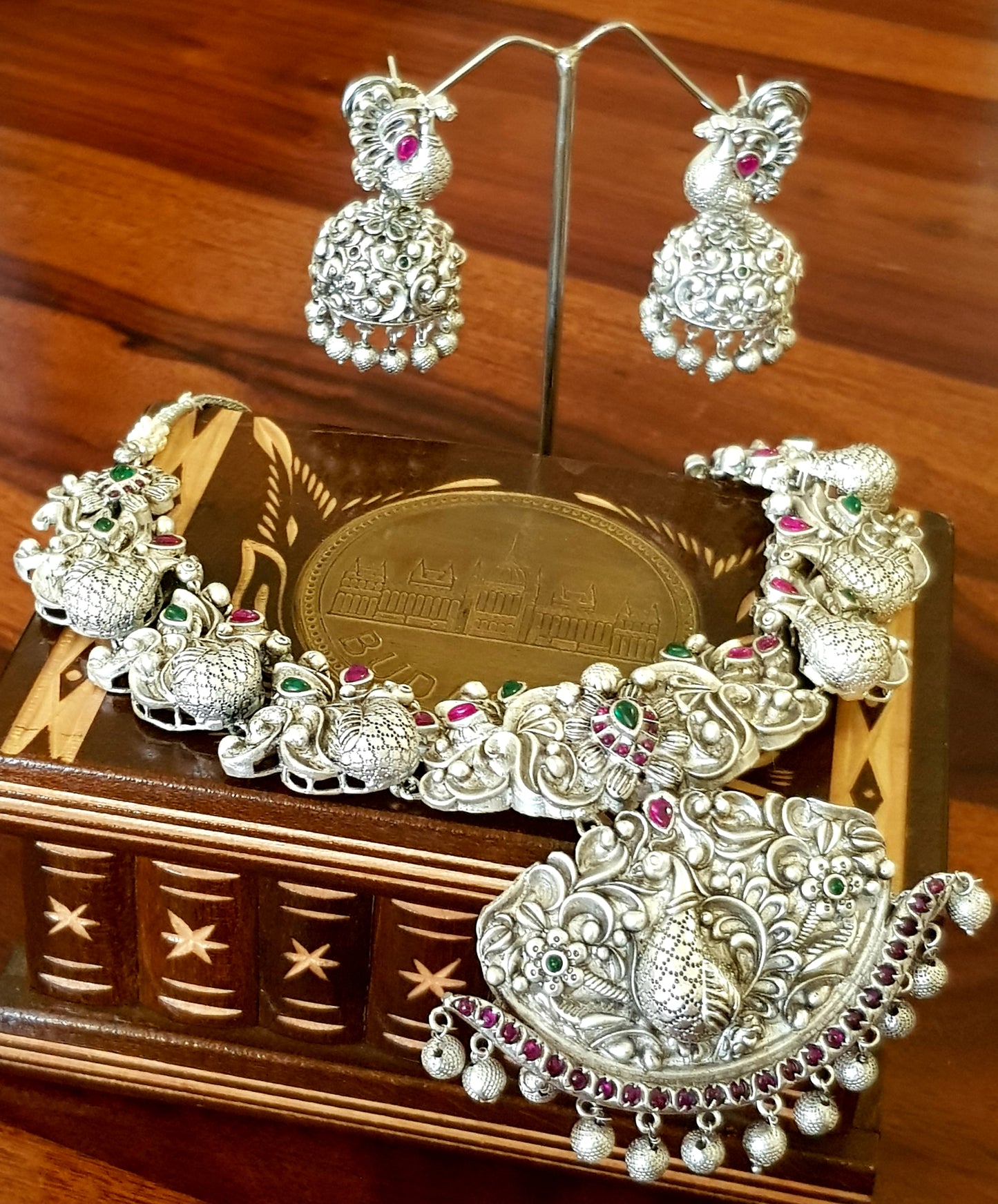 Silver finish temple jewelry set, necklace with peacock motif, green-red stones inlay, matching jhumkas (earrings)