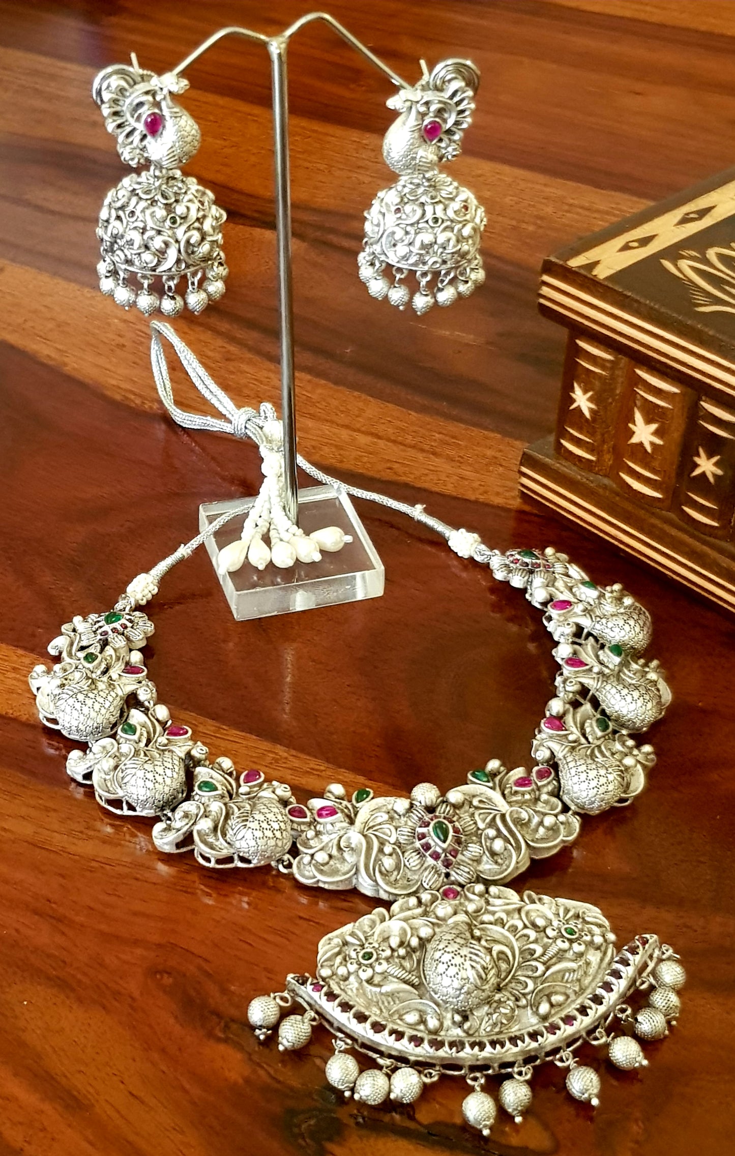 Silver finish temple jewelry set, necklace with peacock motif, green-red stones inlay, matching jhumkas (earrings)