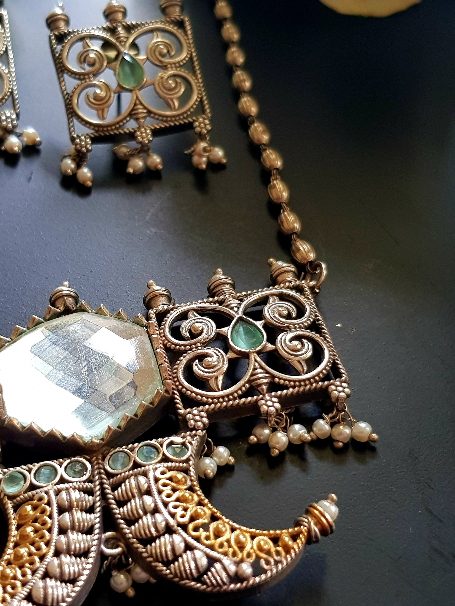 Dual tone set with two curved knives below circular clear stone and square jaali pieces, matching studs (earrings)