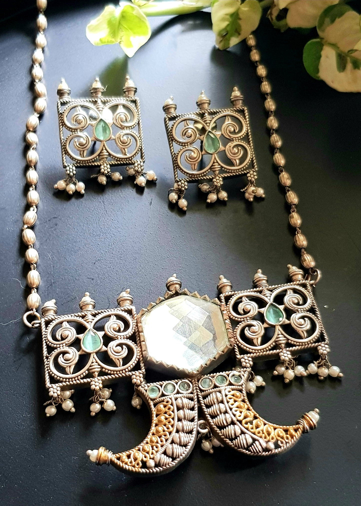 Dual tone set with two curved knives below circular clear stone and square jaali pieces, matching studs (earrings)