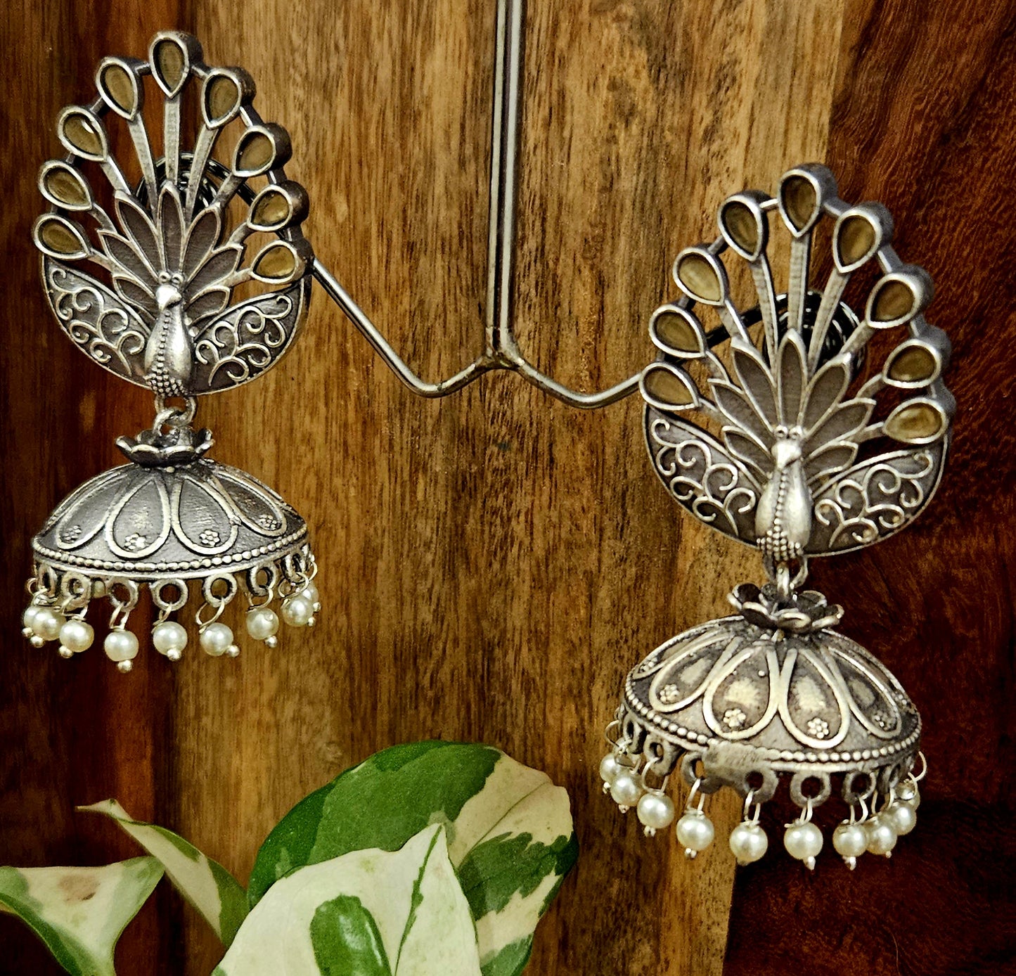 Silver finish jhumka (earrings) with peacock design stud and flat dome