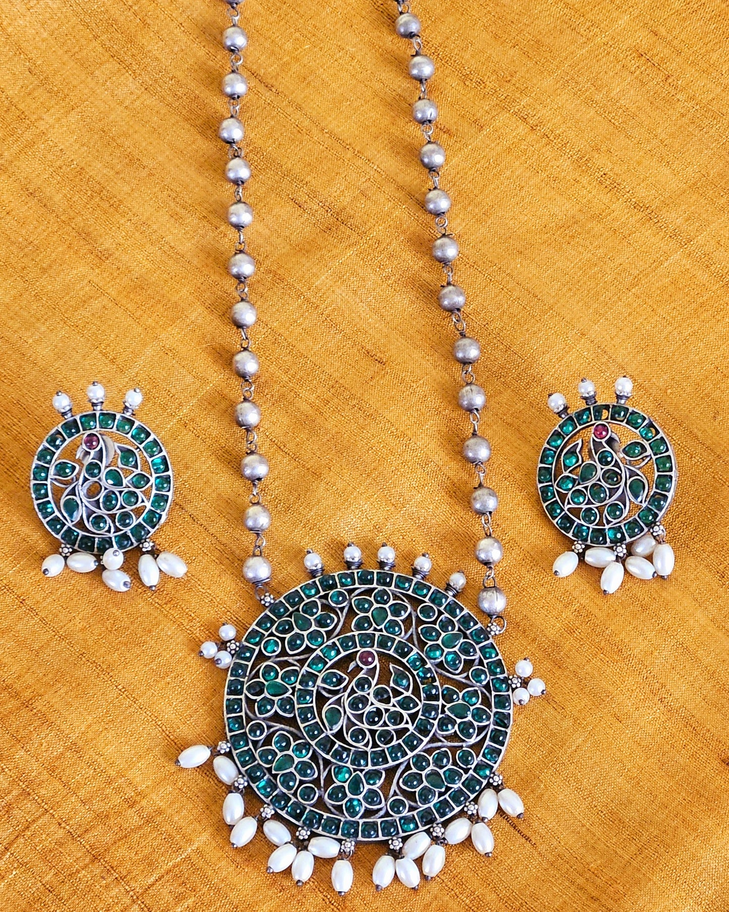 Silver finish long necklace set with big round pendant embellished with green/red stones, matching studs (earrings)