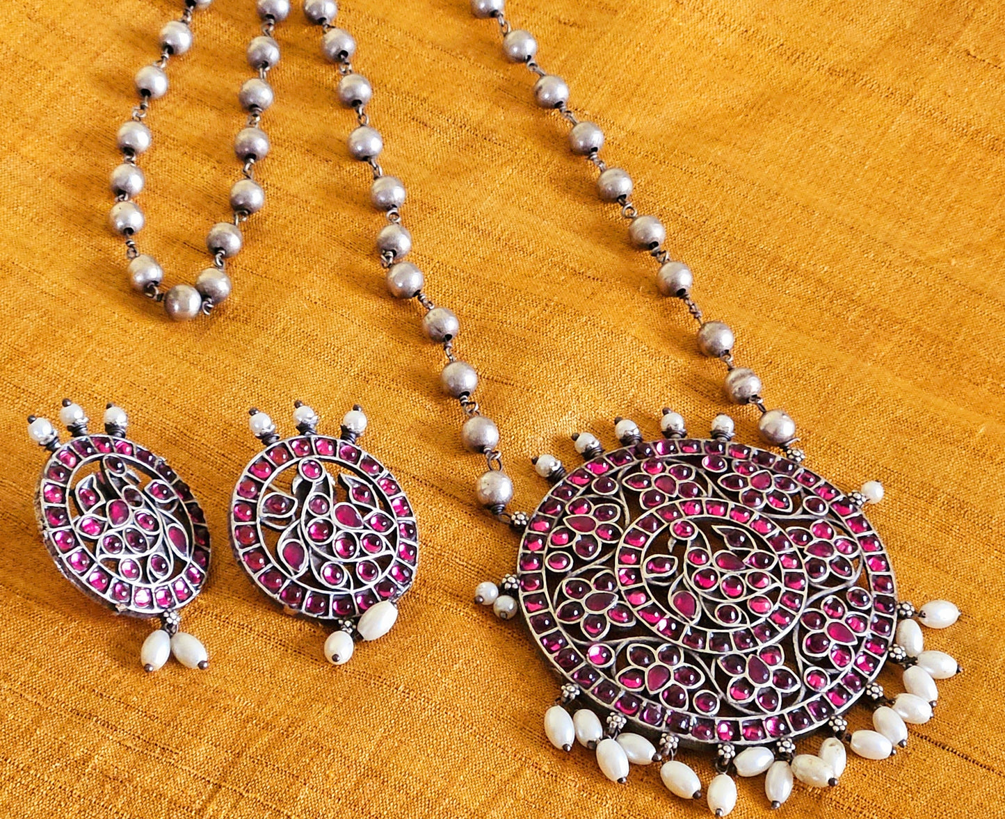 Silver finish long necklace set with big round pendant embellished with green/red stones, matching studs (earrings)