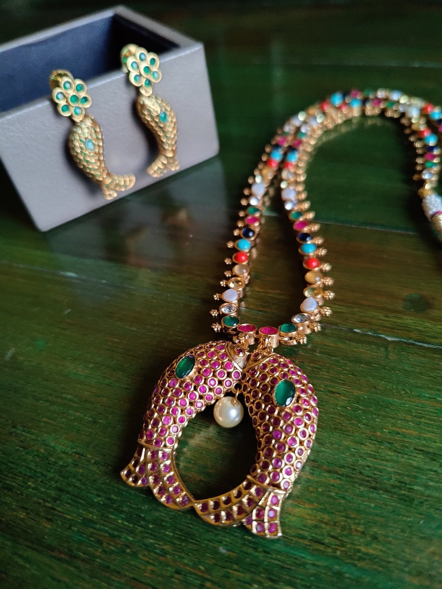 Gold finish fish motif reversible set with navratan stones on one side and emerald green/blue sapphire/ Ruby red stone inlay, matching earrings