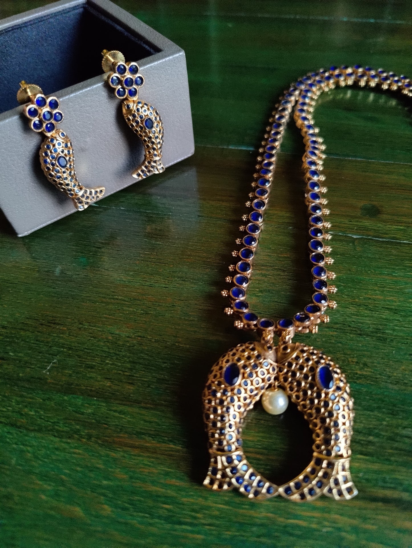 Gold finish fish motif reversible set with navratan stones on one side and emerald green/blue sapphire/ Ruby red stone inlay, matching earrings