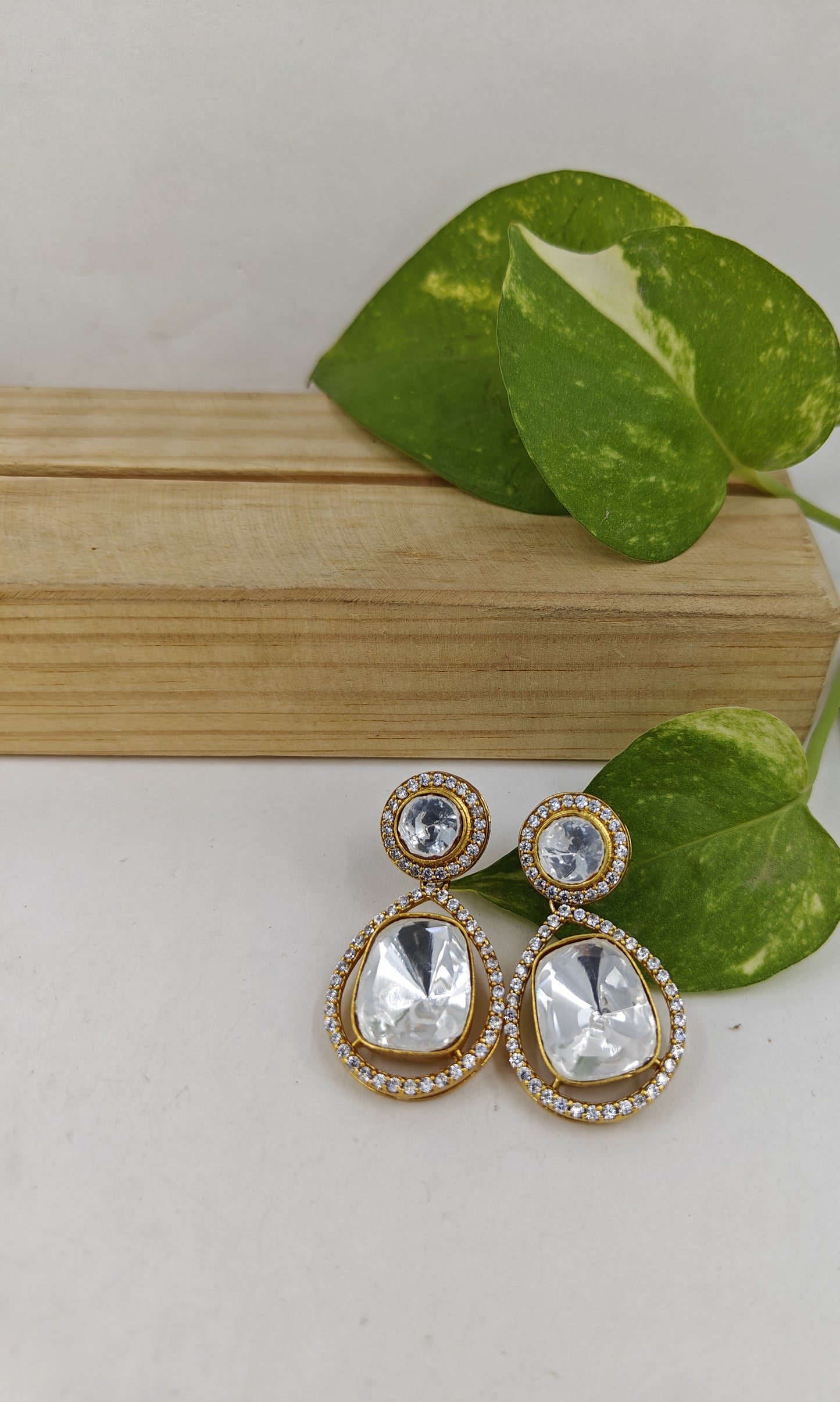 Earrings in gold finish with a moissanite hanging on a round moissanite stud.