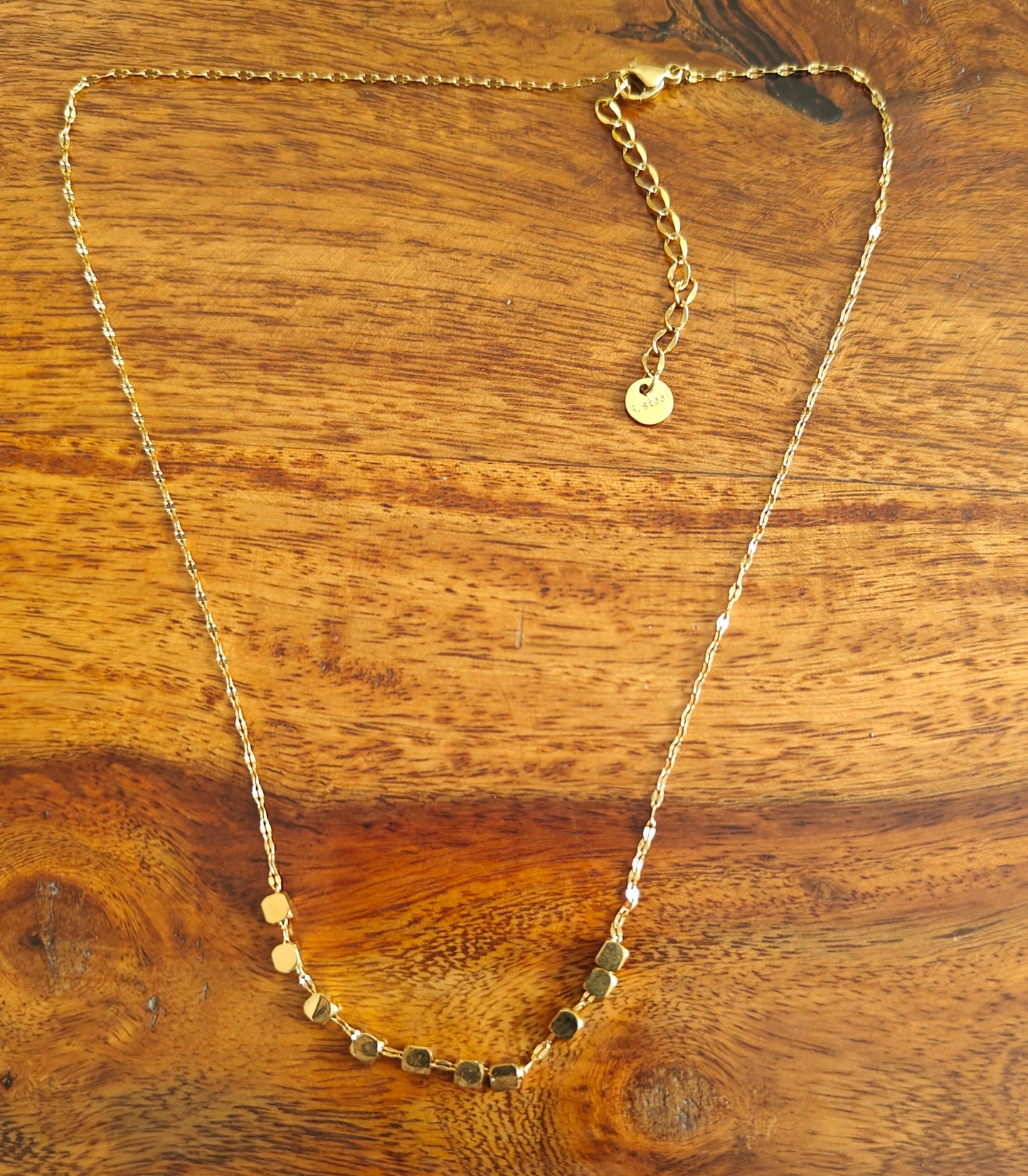 Gold chain with square  pieces on it in centre