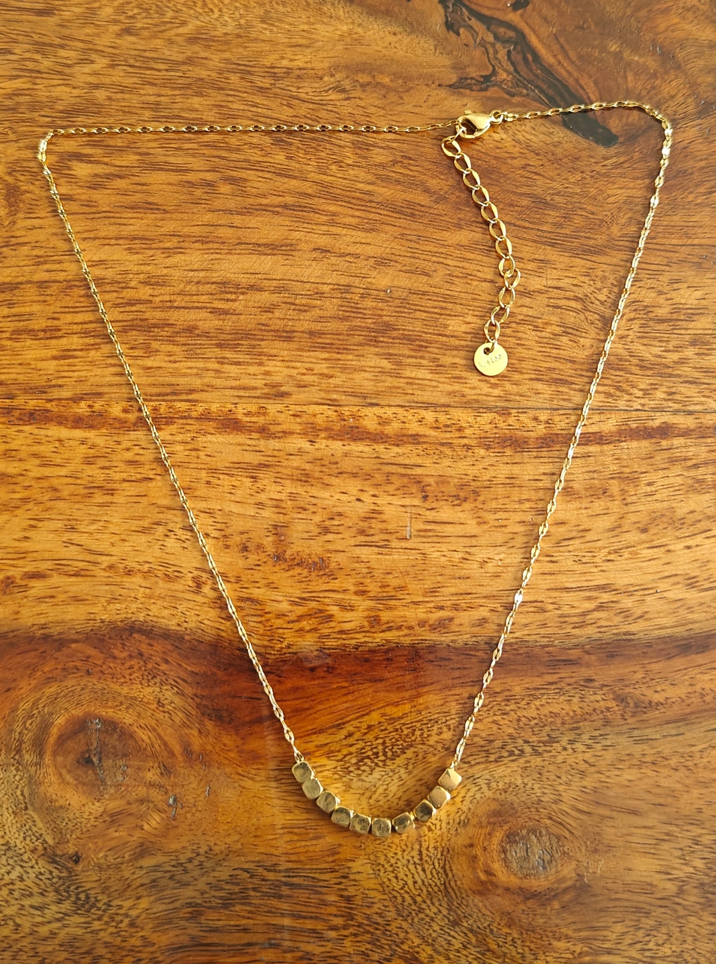 Gold chain with square  pieces on it in centre