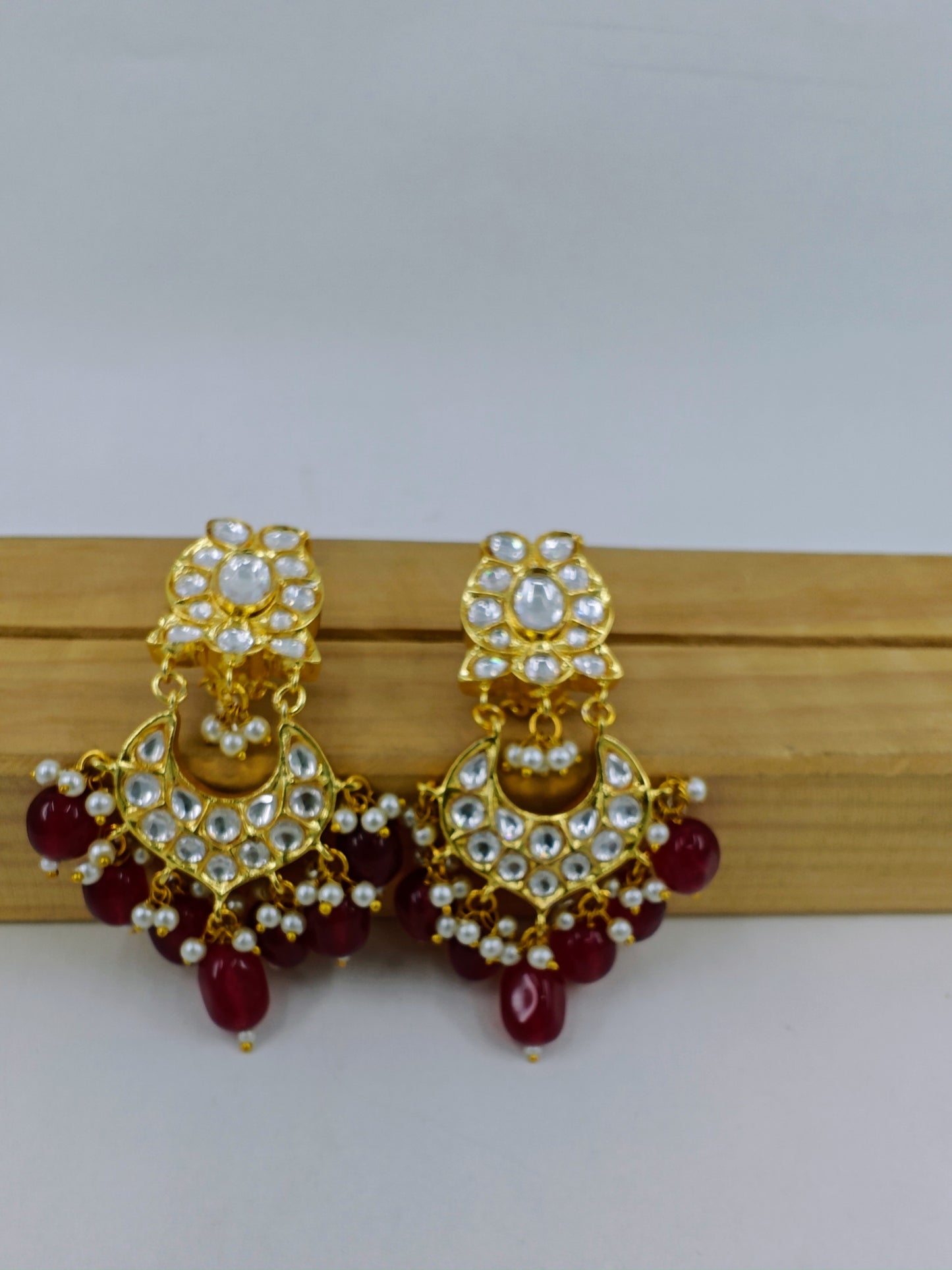 Earrings in gold finish with Kundan and red stone hangings