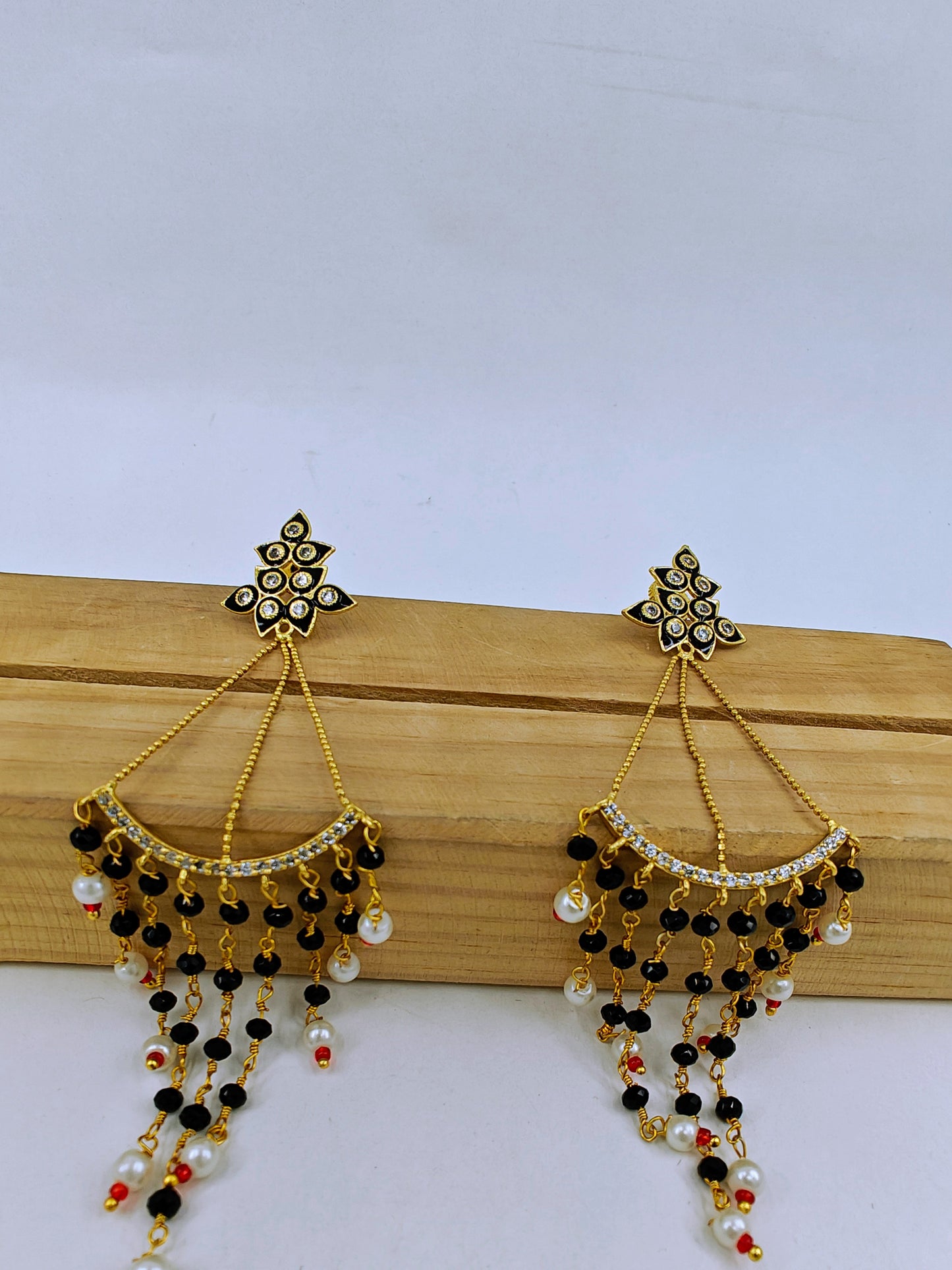 Earrings in gold finish, delicate long danglers with black meenakari and stone hangings