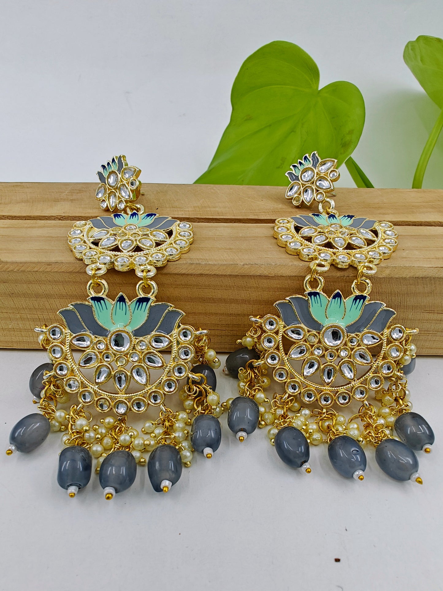 Earrings in golden finish with three lotus flowers in grey meenakari and kundan