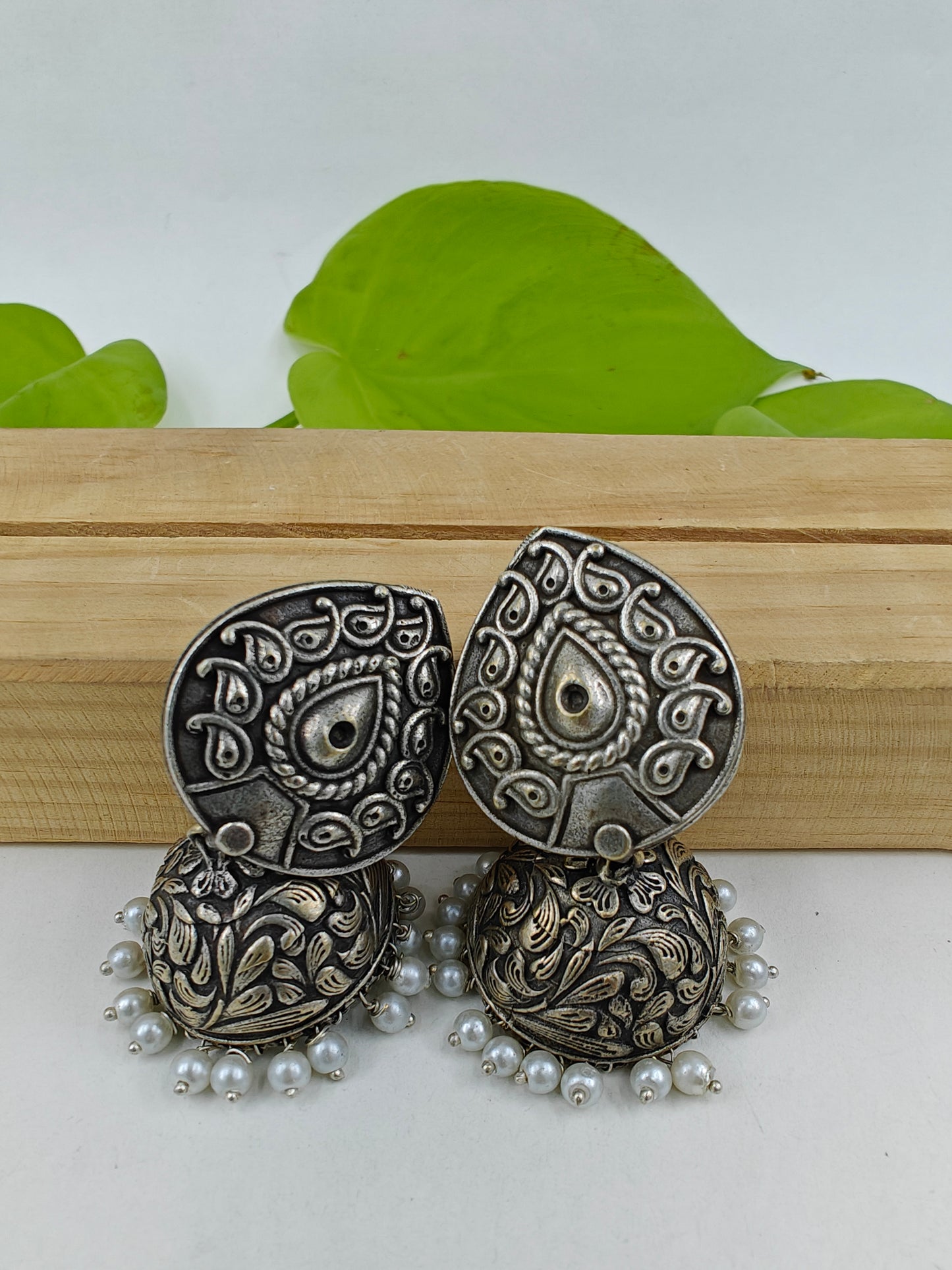 Earrings ( jhumkis) with pearl on drop shaped stud in silver finish