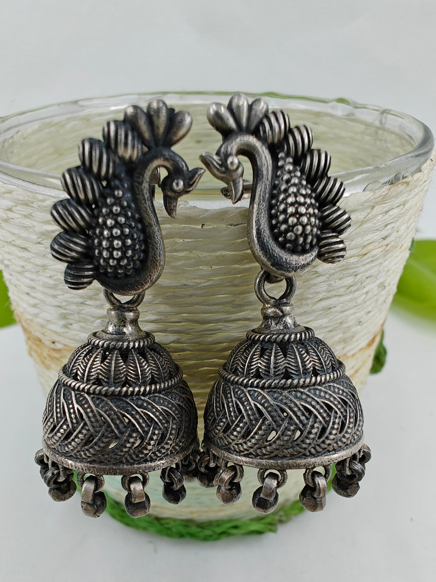 Silver jhumkis (earrings) with bead hanging on peacock studs