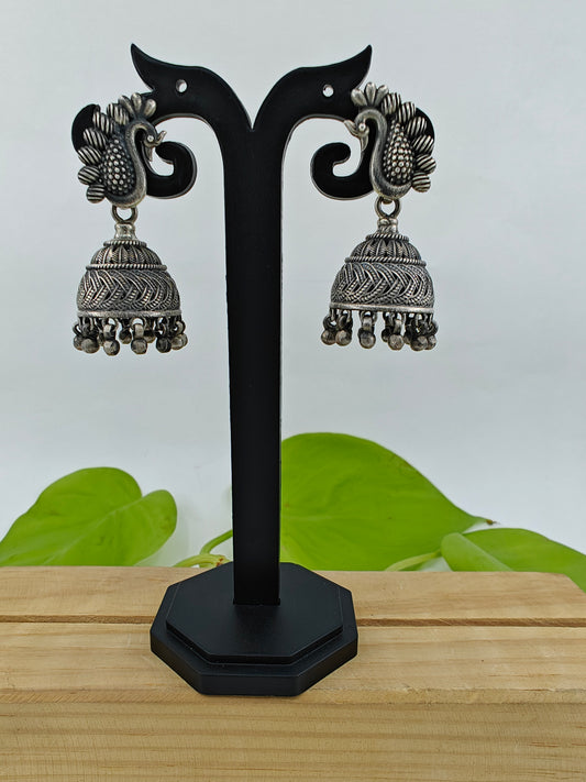 Silver jhumkis (earrings) with bead hanging on peacock studs