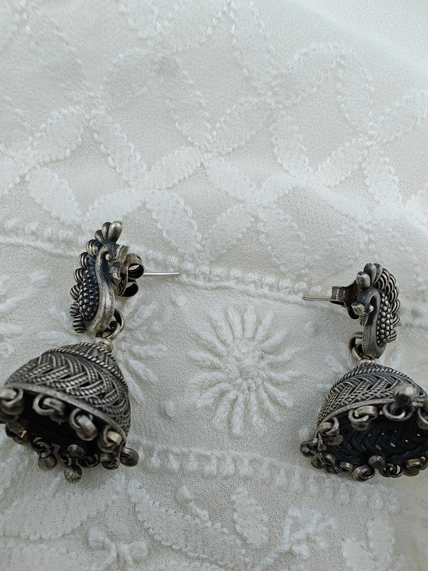 Silver jhumkis (earrings) with bead hanging on peacock studs