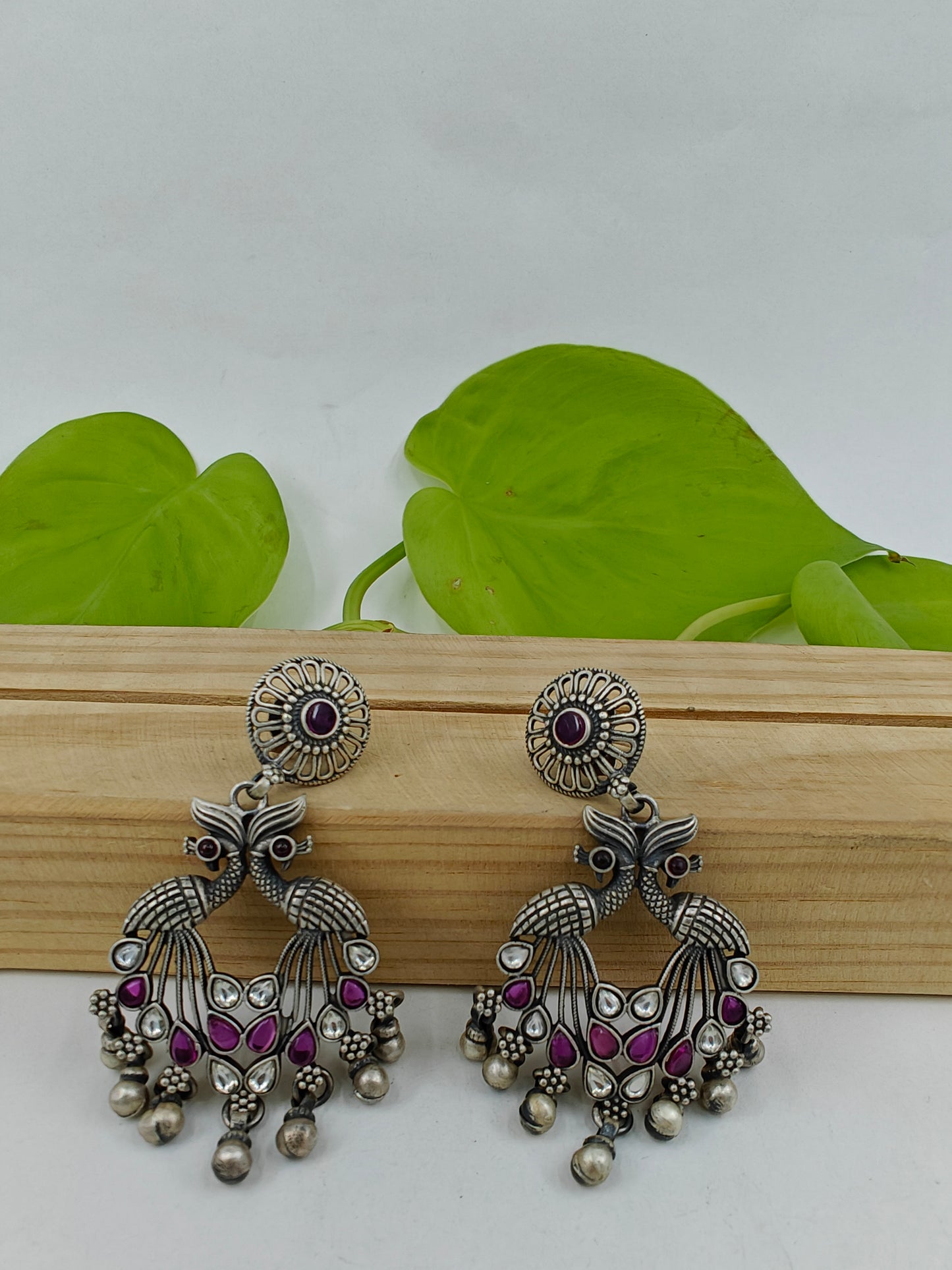 Silver earrings having 2 peacock motif with pink/green and clear stones on a round stud