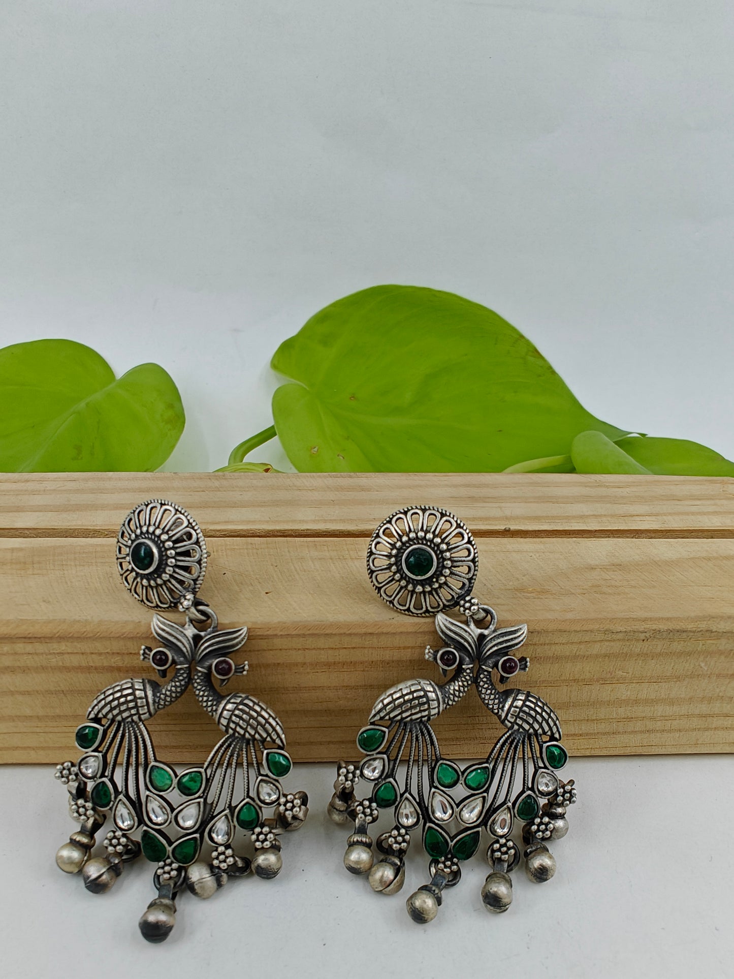 Silver earrings having 2 peacock motif with pink/green and clear stones on a round stud