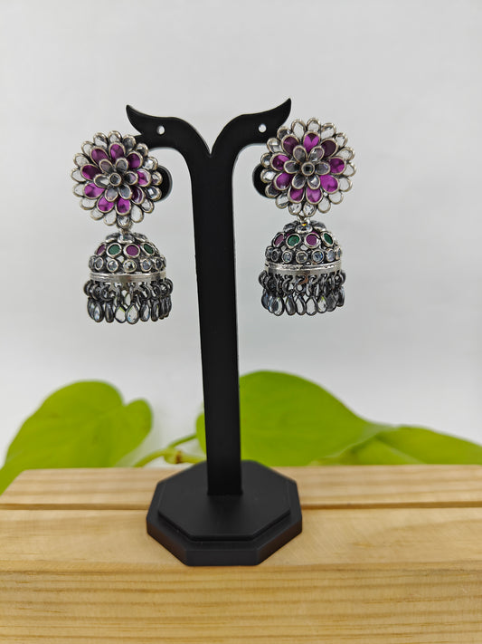 Silver jhumkis (earrings) with red and clear stone petals on a open flower stud