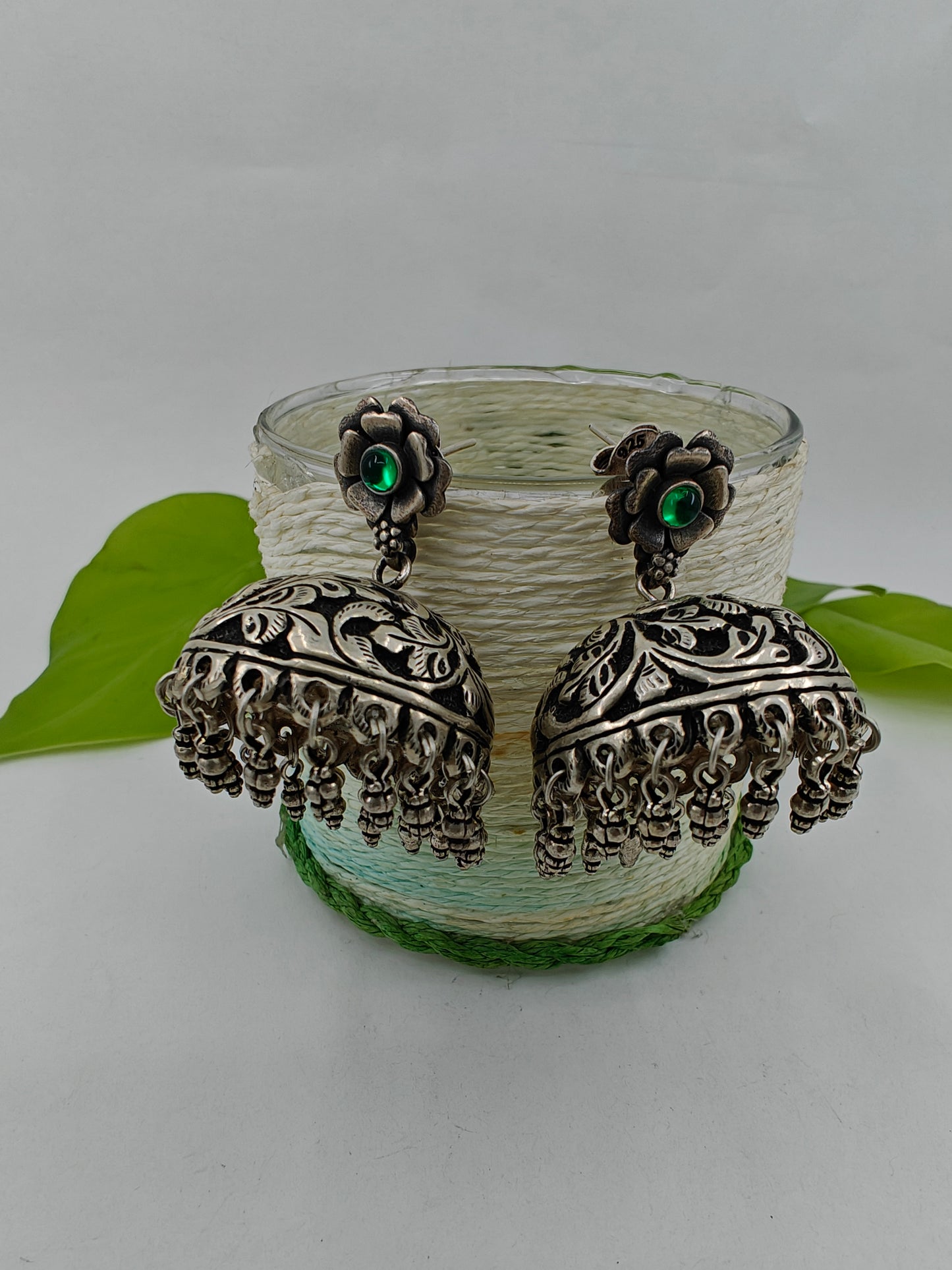 Silver jhumkas (earrings) on a flower stud with green stone