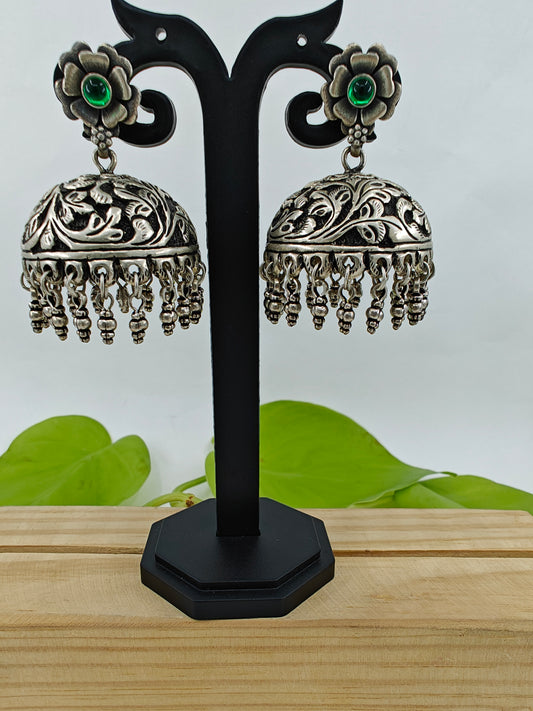 Silver jhumkas (earrings) on a flower stud with green stone