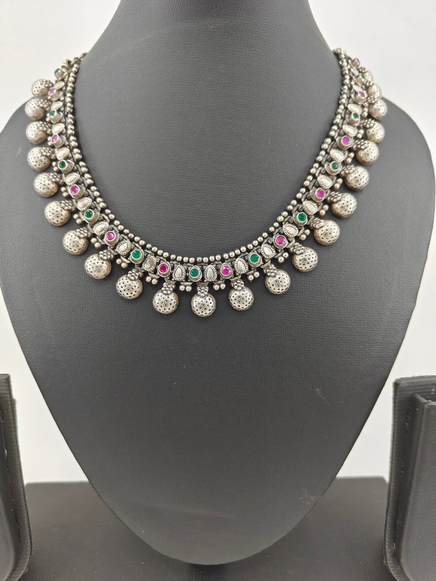 Silver necklace with ruby and emerald inlay and half domes at the bottom