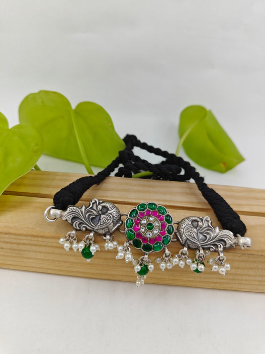 Silver choker necklace with pink and green stone work in center and peacocks on side