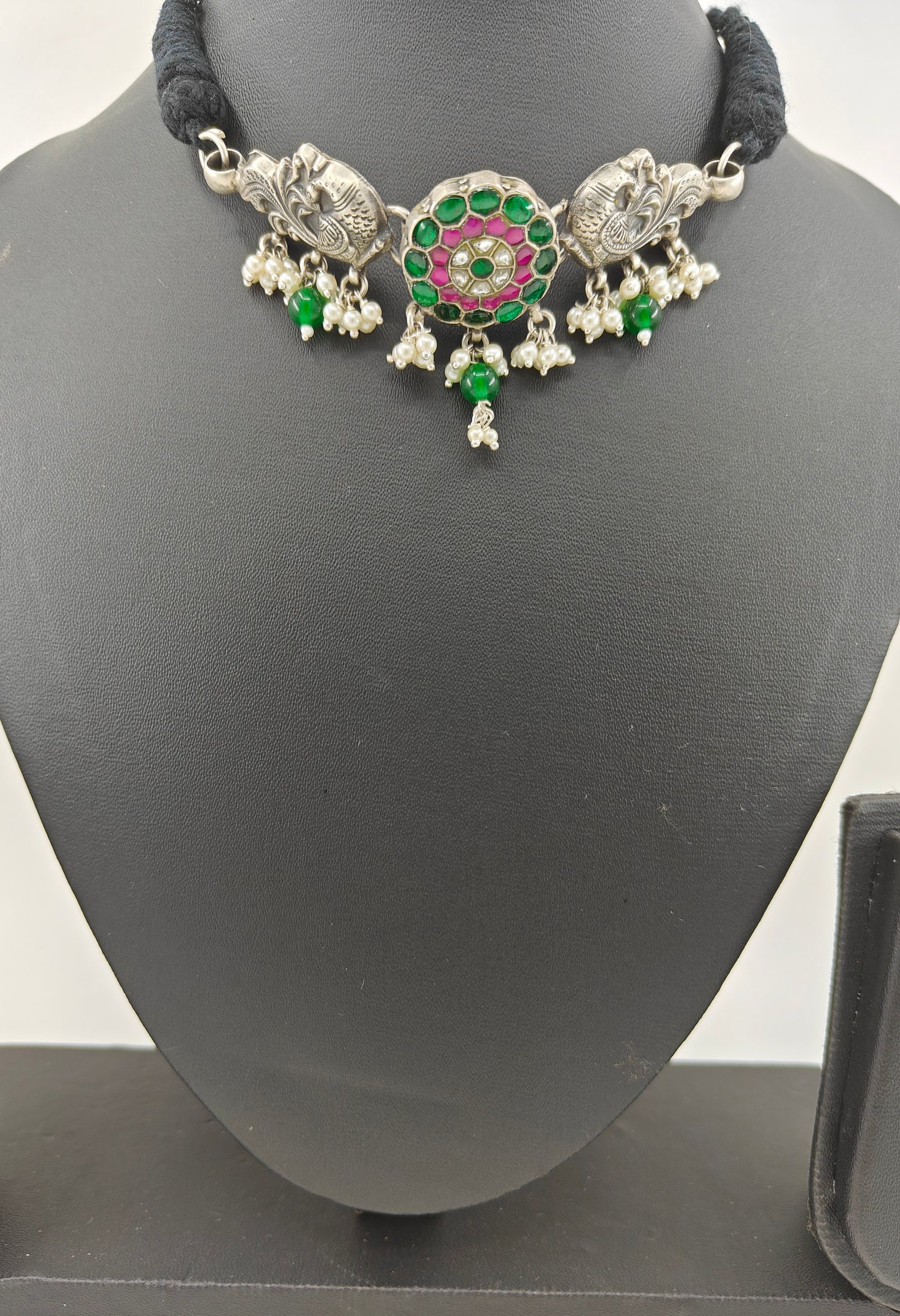 Silver choker necklace with pink and green stone work in center and peacocks on side