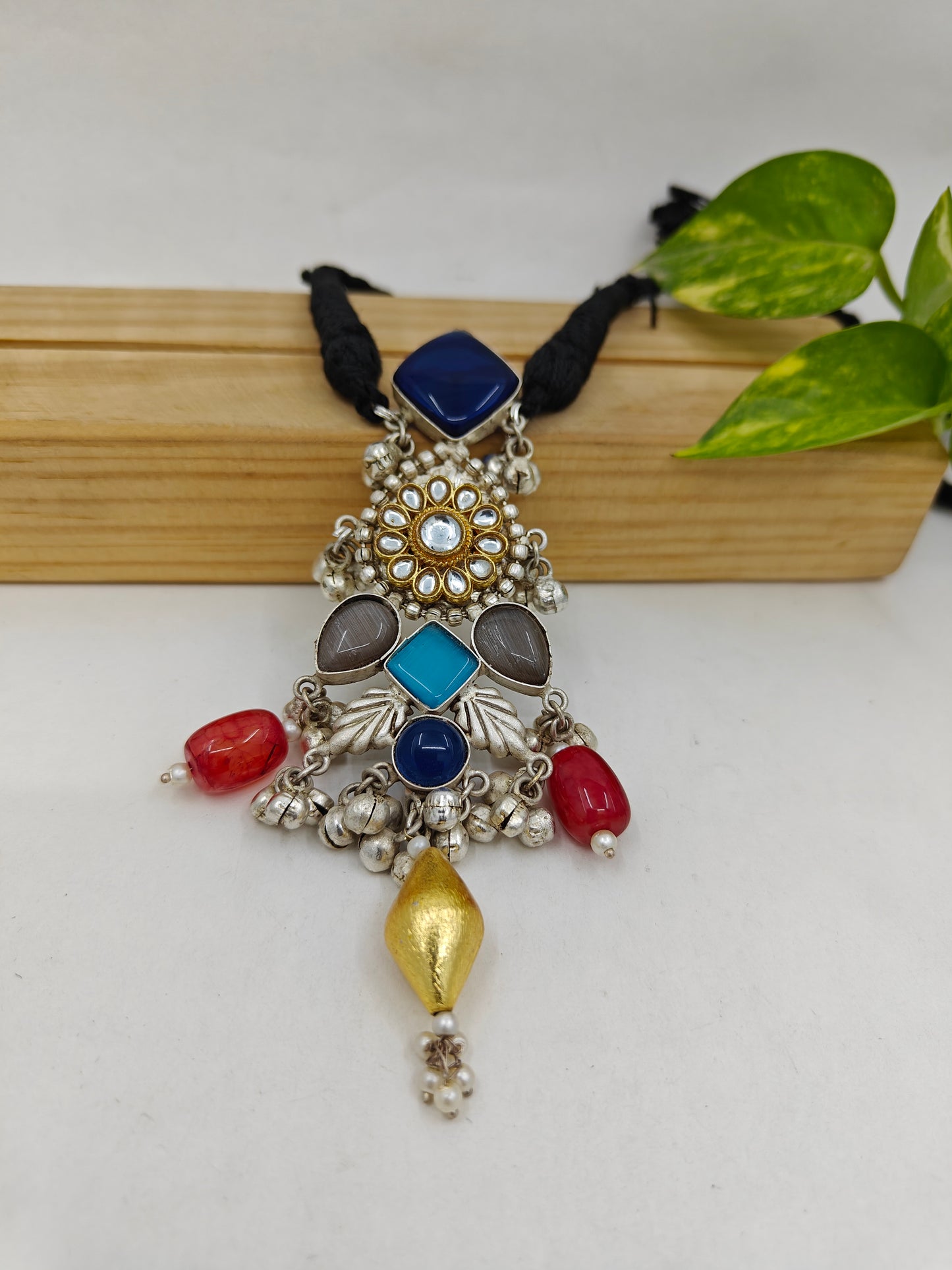 Tilism necklace with a pendant with different coloured stones ,kundan and ghungroos on a black string