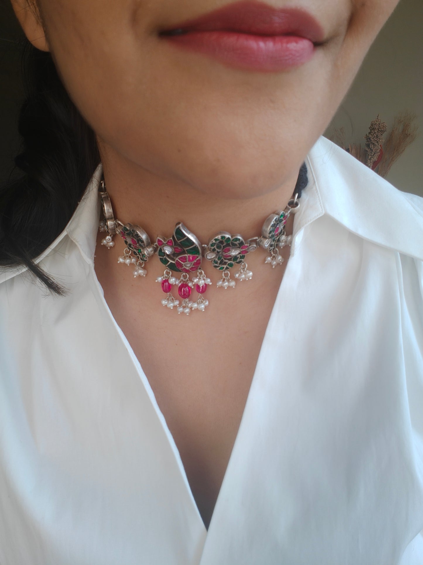 Silver choker necklace with a peacock centerpiece studded with ruby pink and emerald green stones