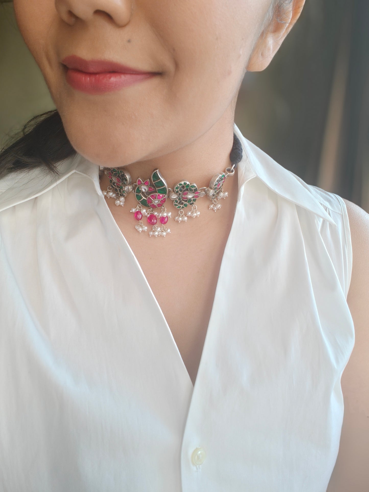 Silver choker necklace with a peacock centerpiece studded with ruby pink and emerald green stones