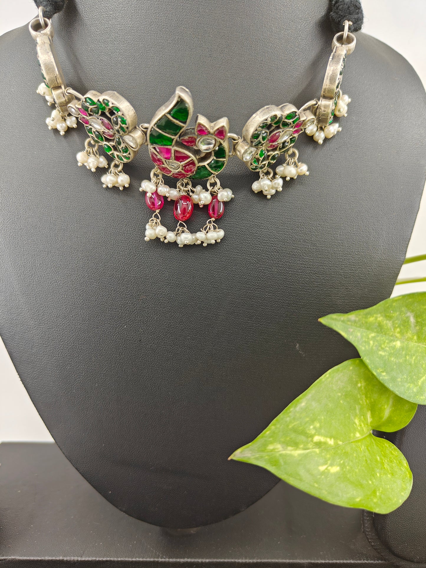 Silver choker necklace with a peacock centerpiece studded with ruby pink and emerald green stones