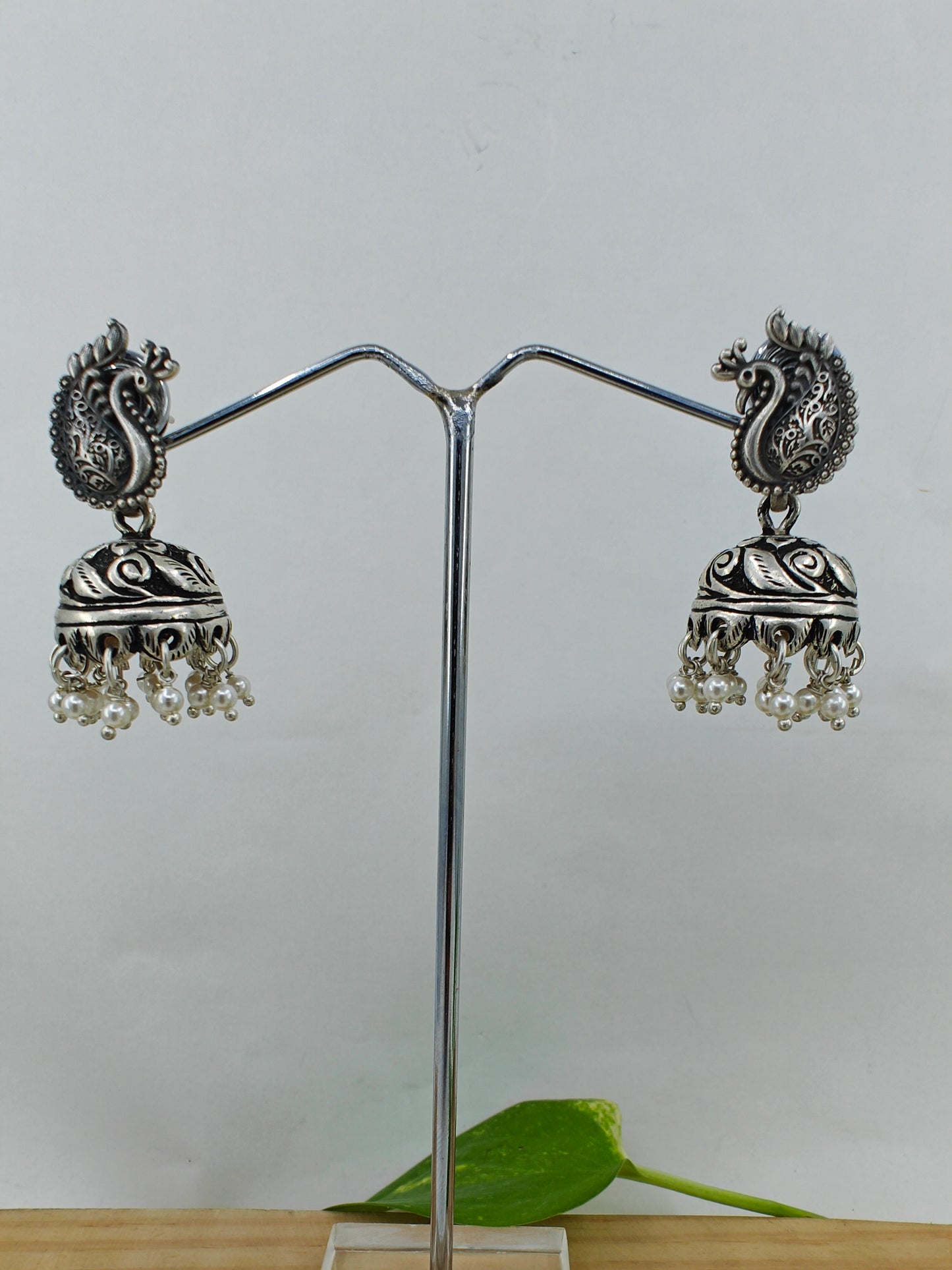 Silver jhumkis (earrings) with carvings on a peacock stud, pearl hangings