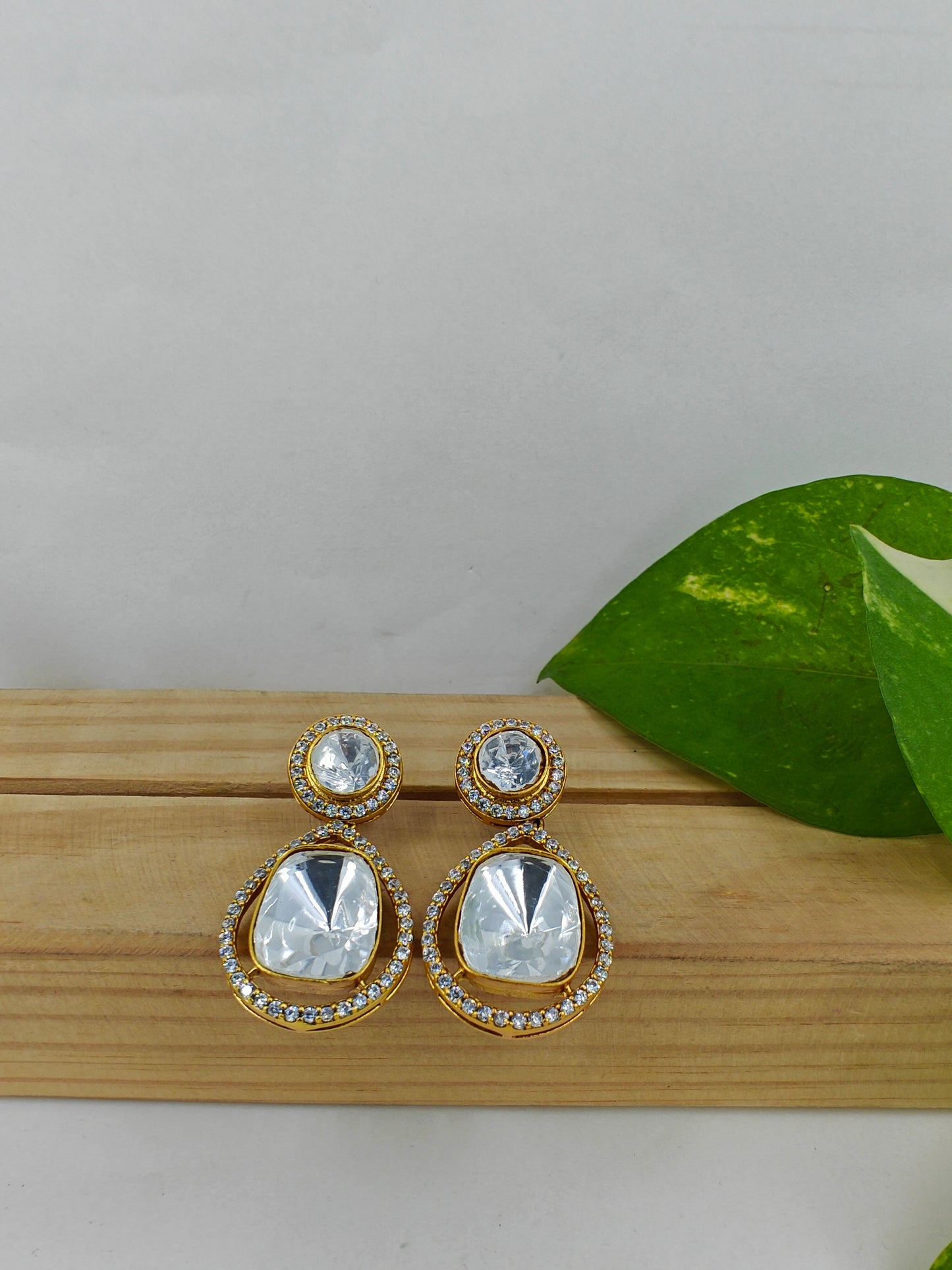 Earrings in gold finish with a moissanite hanging on a round moissanite stud.