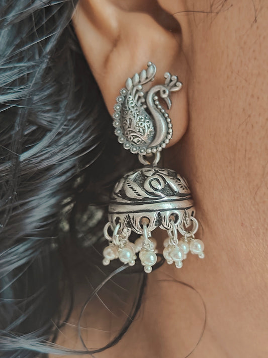 Silver jhumkis (earrings) with carvings on a peacock stud, pearl hangings