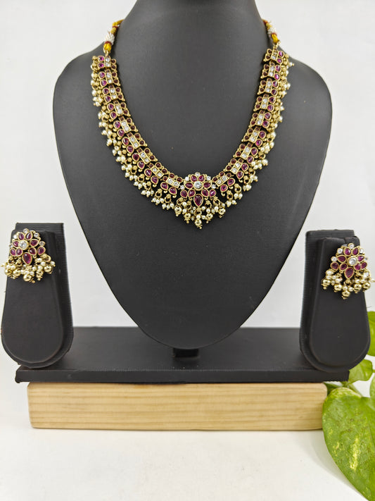 Set in an antique gold finish,red Kemp and white stones along the necklace, delicate set with earl hangings